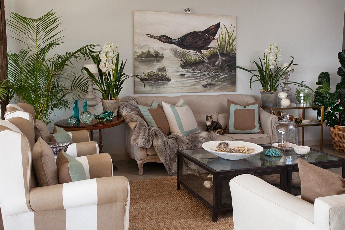Living room with sand-coloured upholstered seating, house plants and picture of aquatic bird