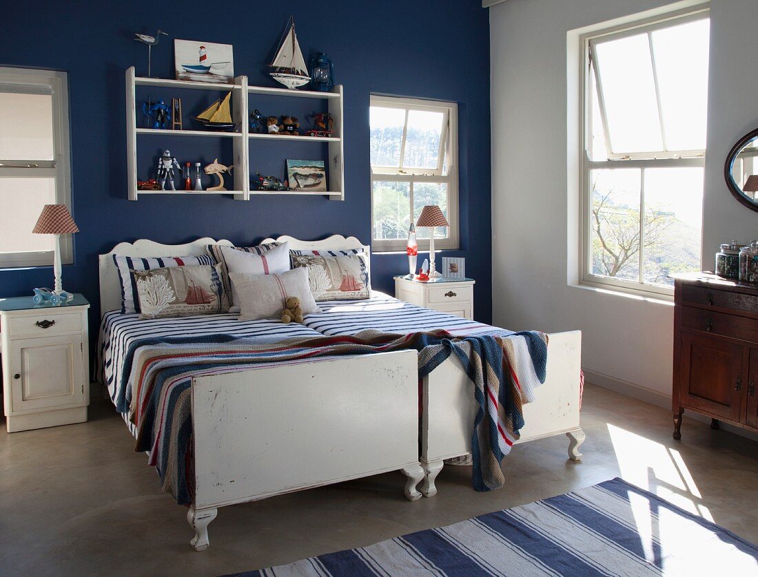 Zwei Einzelbetten nebeneinander vor dunkelblau getönter Wand im Schlafzimmer mit nautischem Charme