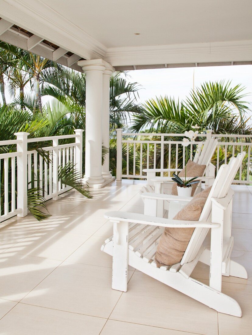 Veranda im Hamptons-Style mit zwei Adirondack Chairs umgeben von Palmen