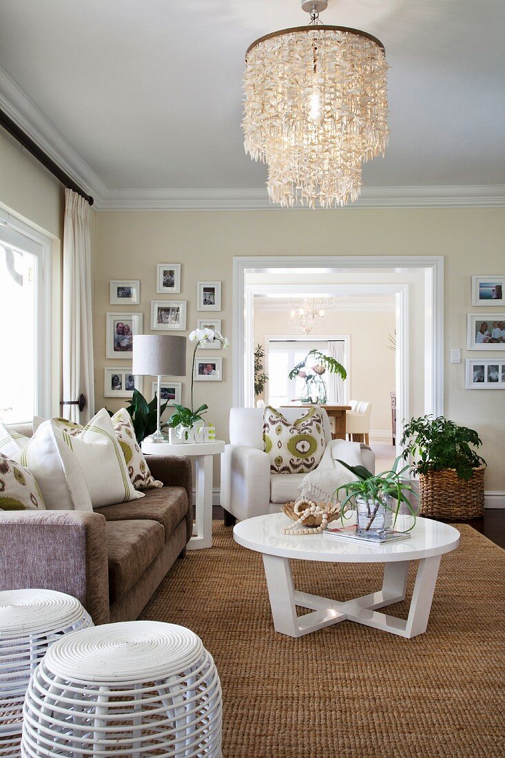 Exotisches Wohnzimmer mit Muschellampe, Sisalteppich und weißen, modernen Möbeln