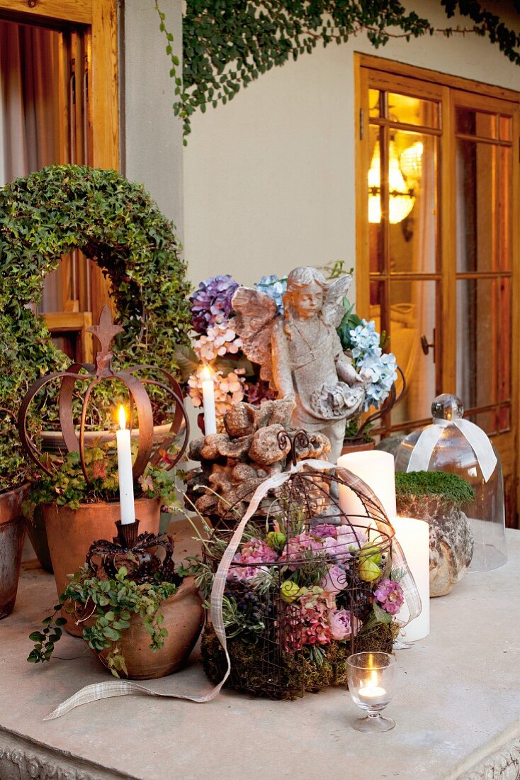 Weihnachtlich dekorierter Terrassentisch mit Blumengesteck in Drahtkorb und brennende Kerzen