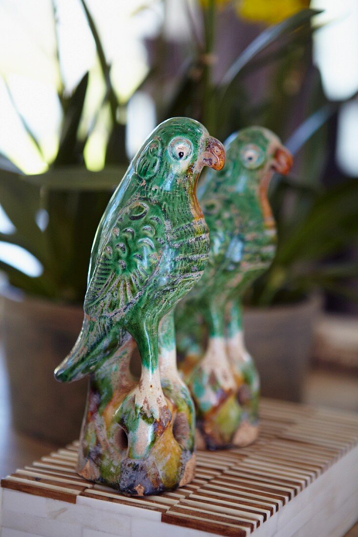 Bemalte Papageienfigur aus Keramik vor Spiegel