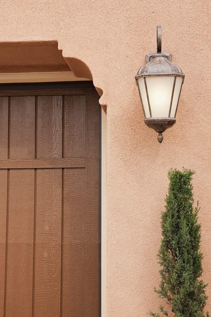 Detail of closed brown door with wall lantern at Irvine; California; USA