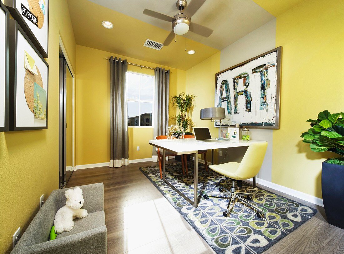 Gelbgrün getöntes Arbeitszimmer - Drehstuhl in passender Farbe und moderner Tisch auf gemustertem Teppichläufer, seitlich zierlicher Diwan mit Stofftier