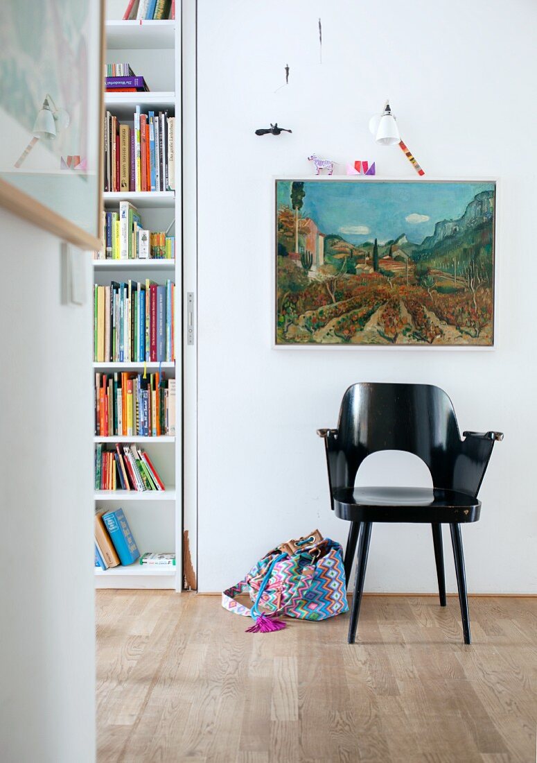 Black-painted retro armchair below landscape painting on wall