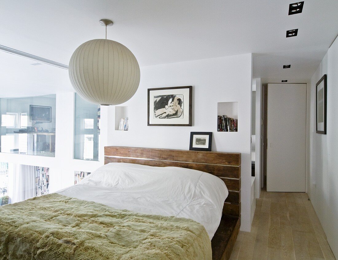Bedspread on double bed below white spherical lamp in bedroom