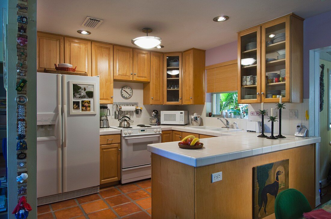 Küche mit Einbauschränken aus hellem Holz sowie weißem Herd, Kühlschrank & Arbeitsplatte