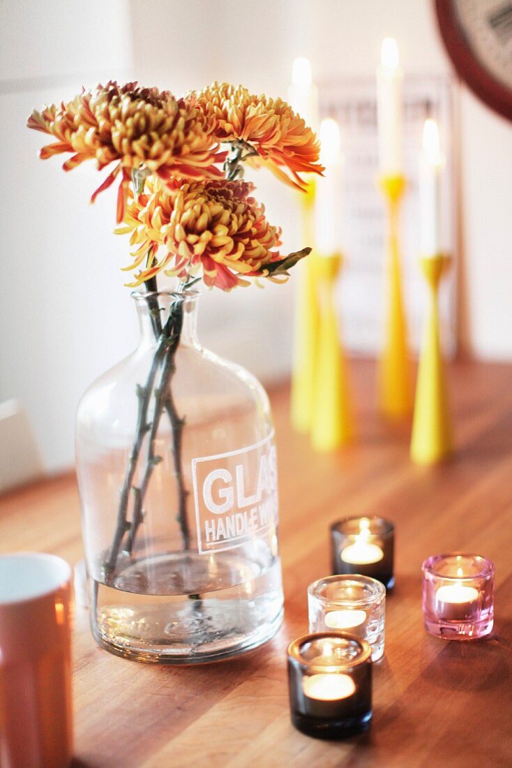 Simple, autumnal flower arrangement with tealights on wooden table