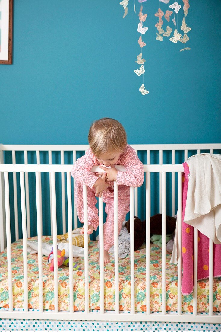 Little girl climbing over side of crib