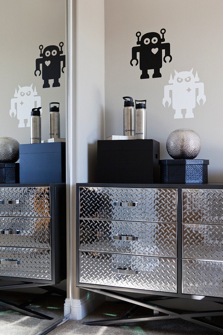 Spiegelwand & silberne Kommode an Wand mit aufgemalten Robotern in Schablonentechnik