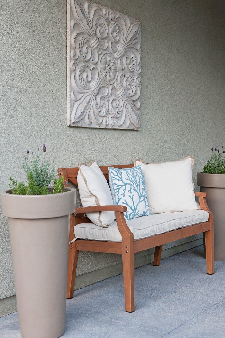 Cushions on sofa and potted plants against wall