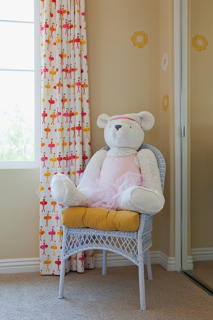 Teddybar im Tütü auf Stuhl sitzend in der Ecke eines Mädchenzimmers