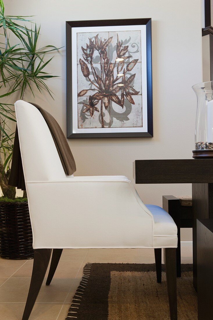 Weisser moderner Armlehnstuhl an braunem Esstisch in Wohnraum mit Wandbild