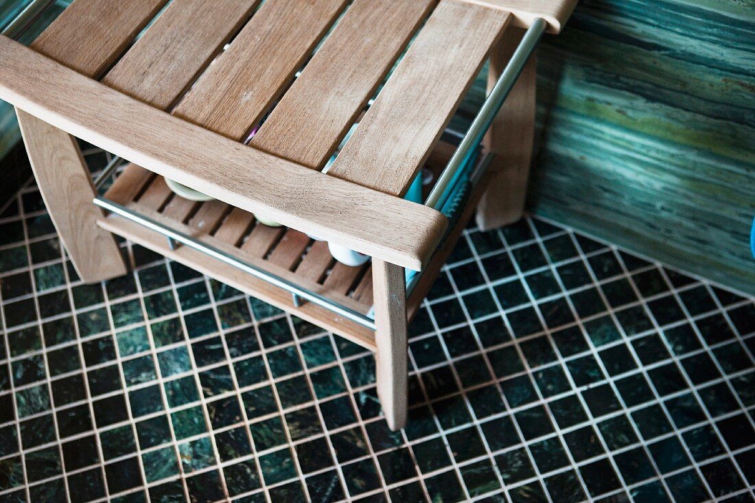 Holzbank auf Mosaikboden in Badezimmer