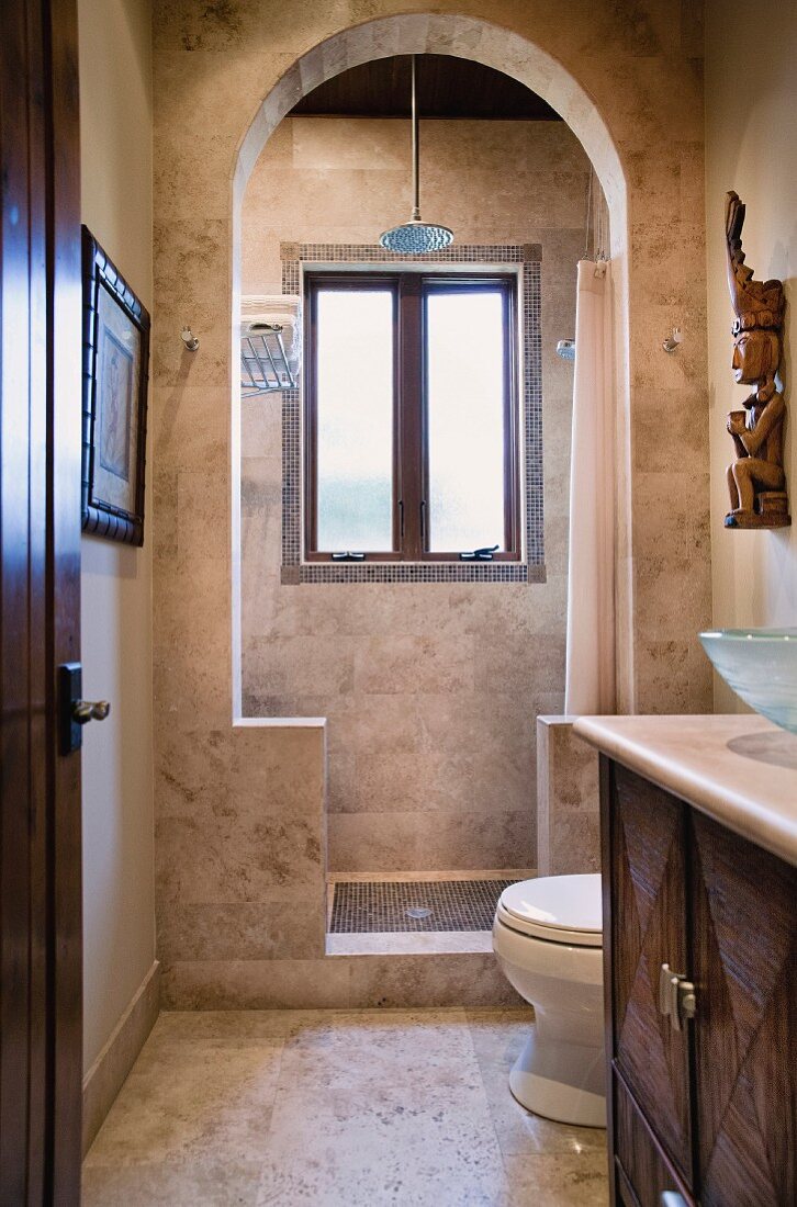 Gefliestes Badezimmer in Brauntönen mit Waschtisch & bogenförmigen Durchgang zur Dusche