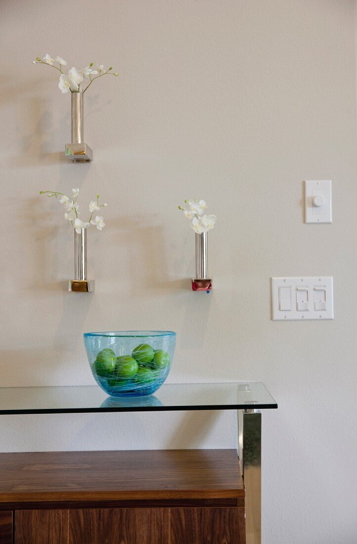 Vases on white wall and bowl on cabinet