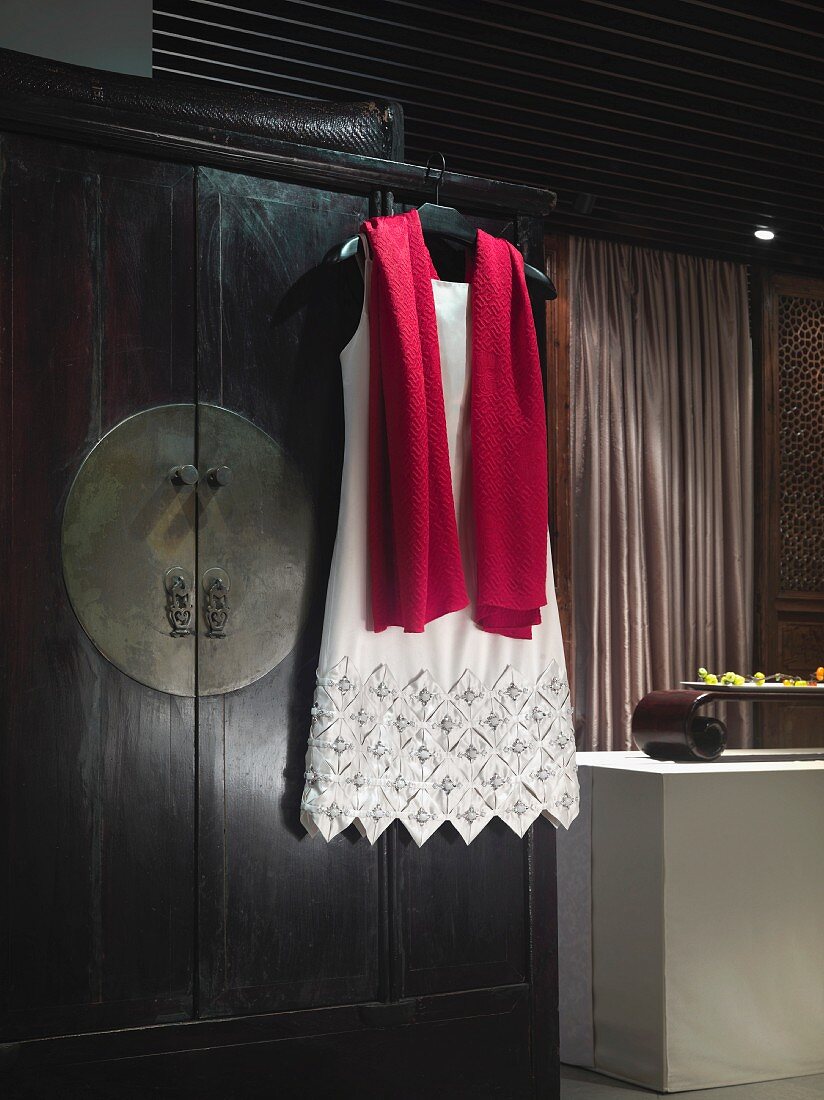 Elegantes Abendkleid und Schal auf Kleiderbügel an Schrank hängend