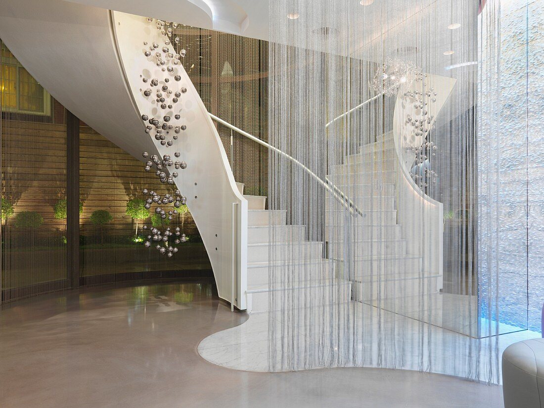 Wendeltreppe in Luxushotel mit Fadenvorhang & Dekoobjekt aus Kugeln