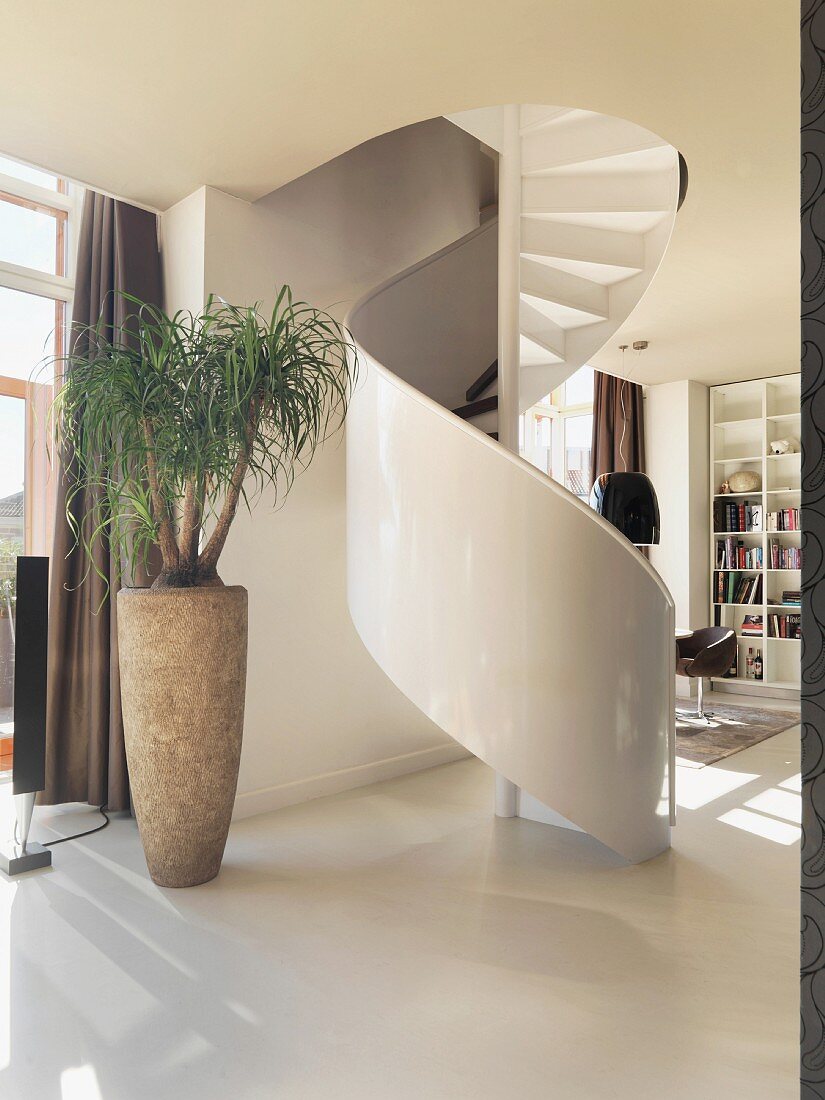 Spiral stairs in hallway with view of seating area in background