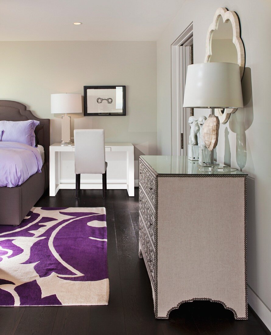 Bedroom in shades of gray with purple accents, bed, dressing table & silver chest of drawers