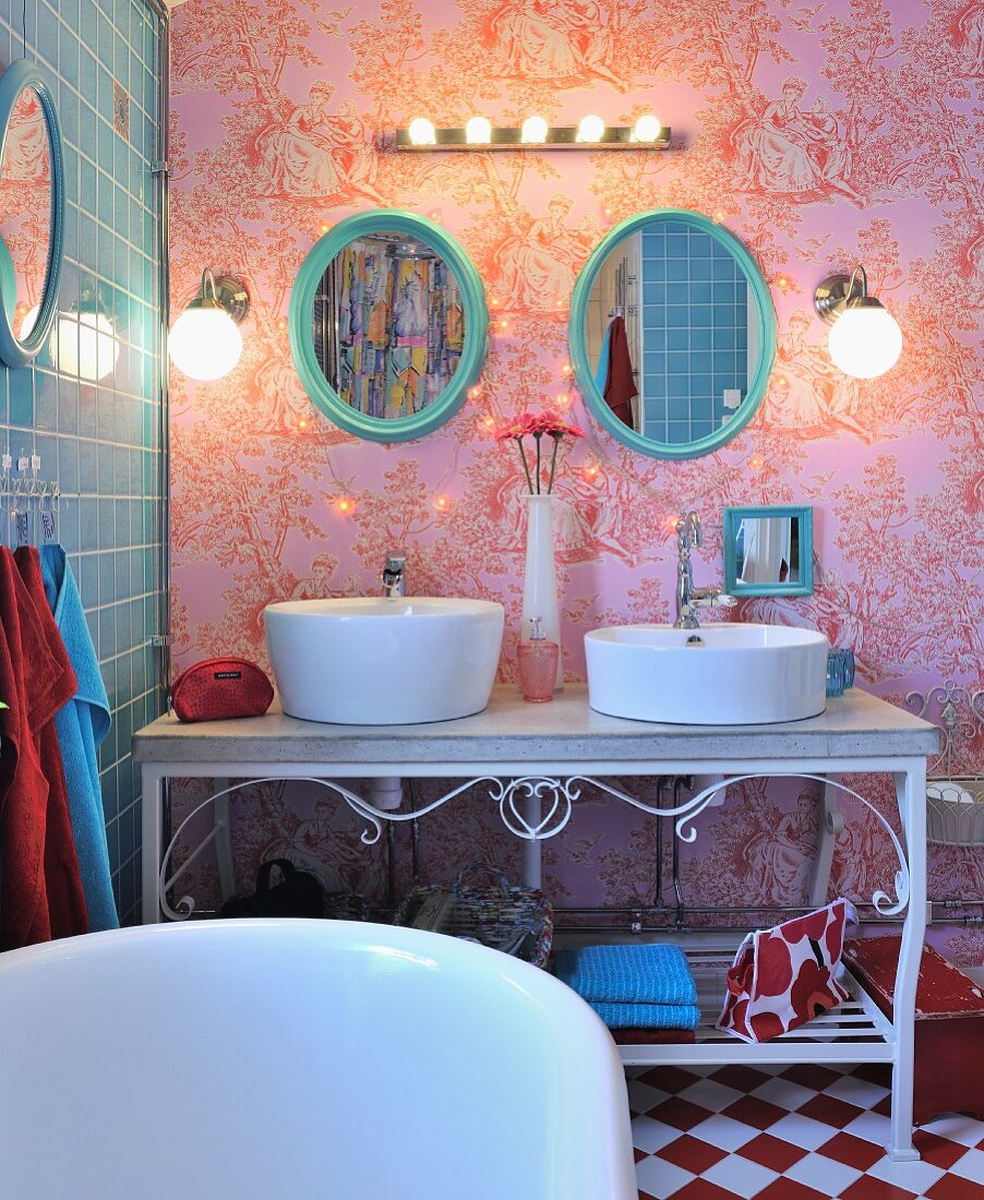 Basins on ornate metal washstand against toile de jouy wallpaper with blue-tiled wall to one side