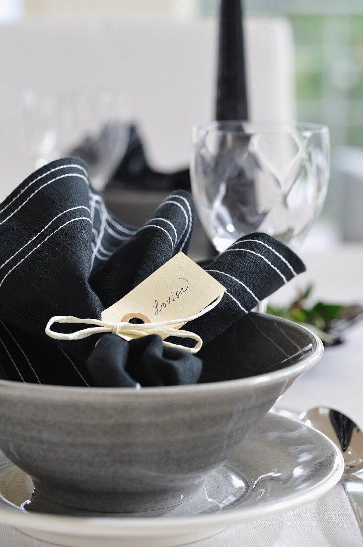 Black napkin with name tag in grey ceramic dish with matching plate