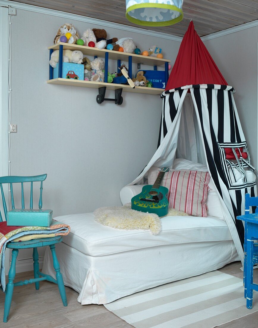 Child's bed below canopy in corner