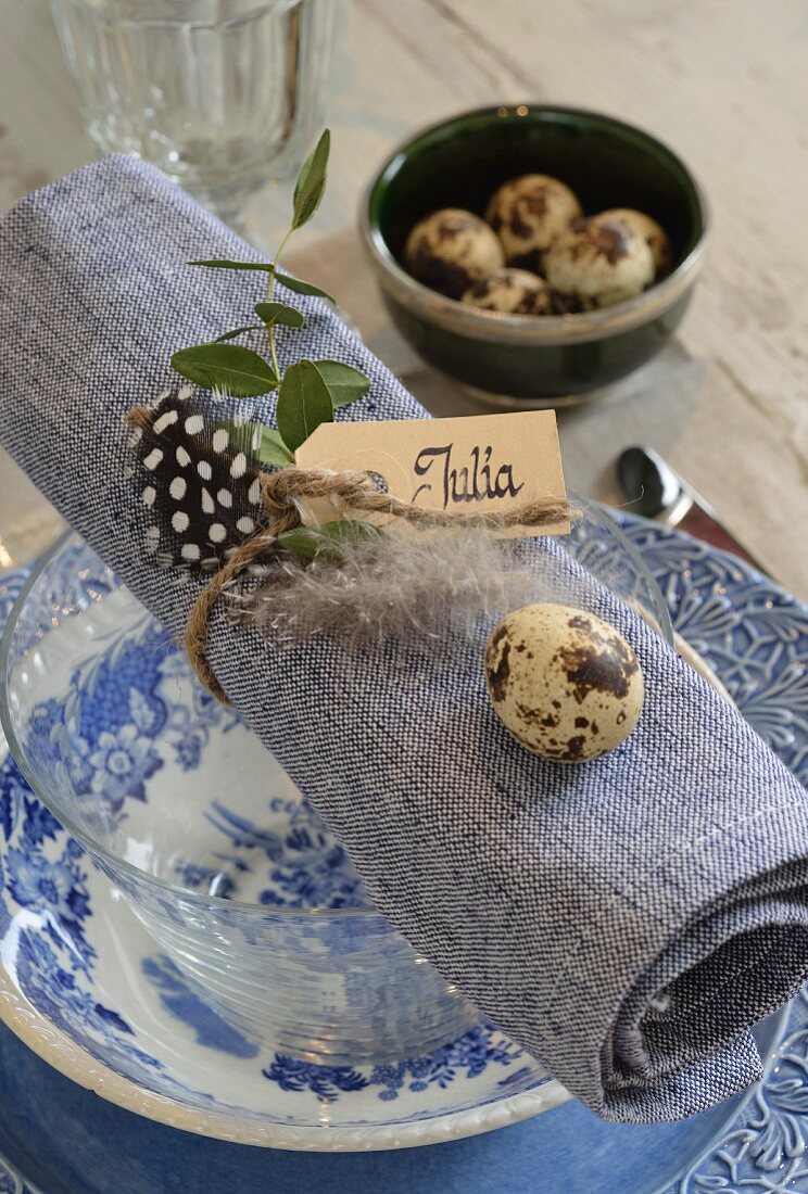 Place setting with blue and white crockery, quail eggs on napkin and name card