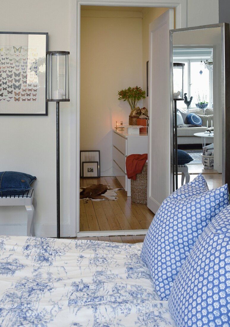 Doppelbett mit blau-weisser Bettwäsche, dahinter Spiegel und angrenzende Ankleide