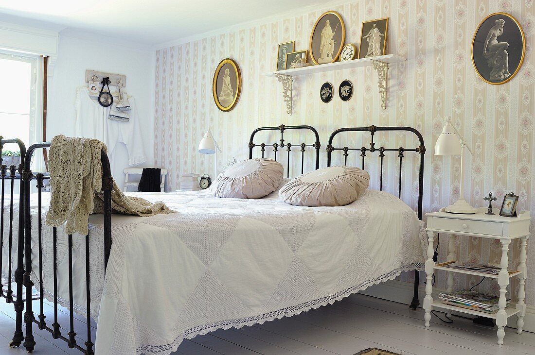 Einzelbetten mit schwarzem Gittergestell nebeneinander gestellt, vor tapezierter Wand in nostalgischem Schlafzimmer