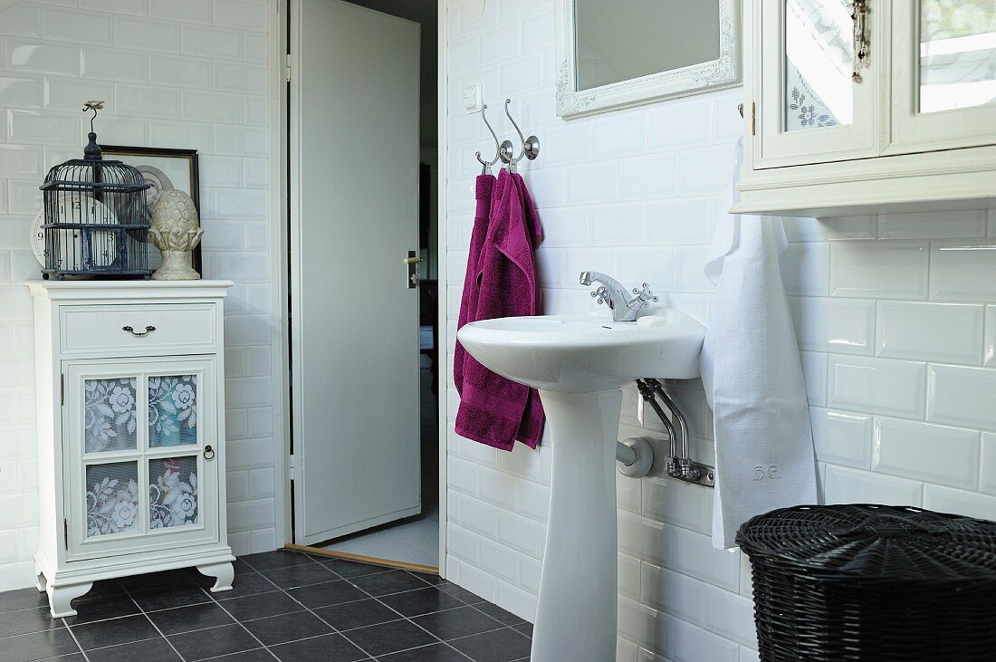 Pedestal sink against white-tiled wall in vintage-style bathroom