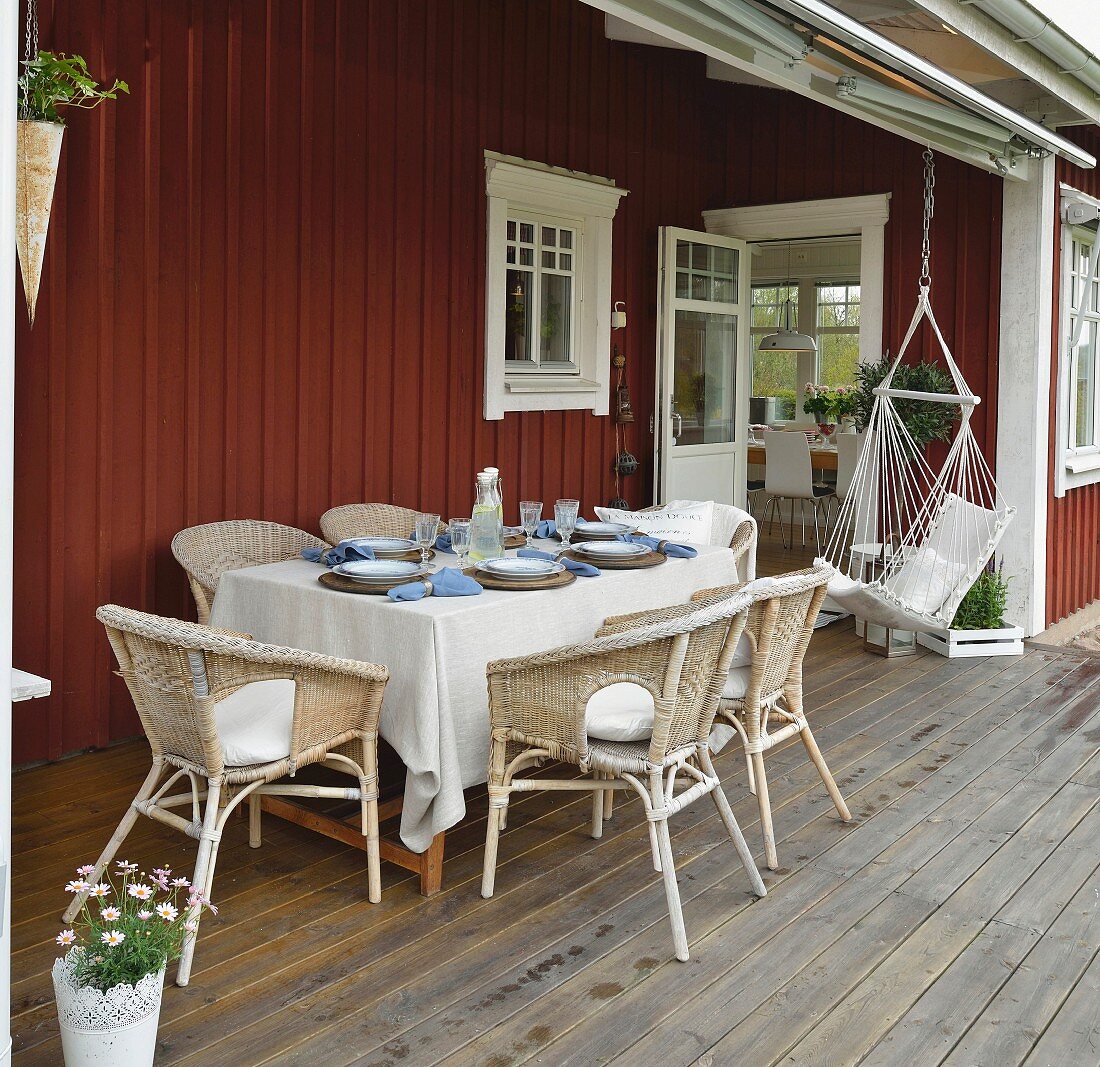 Set table, wicker chairs and hammock chair on veranda of Swedish house