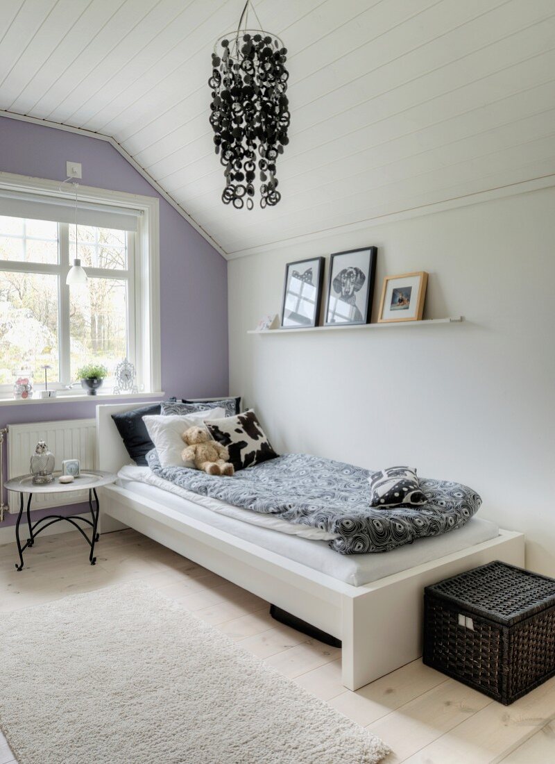 Tray table next to bed in girl's attic bedroom with white and pale lilac walls
