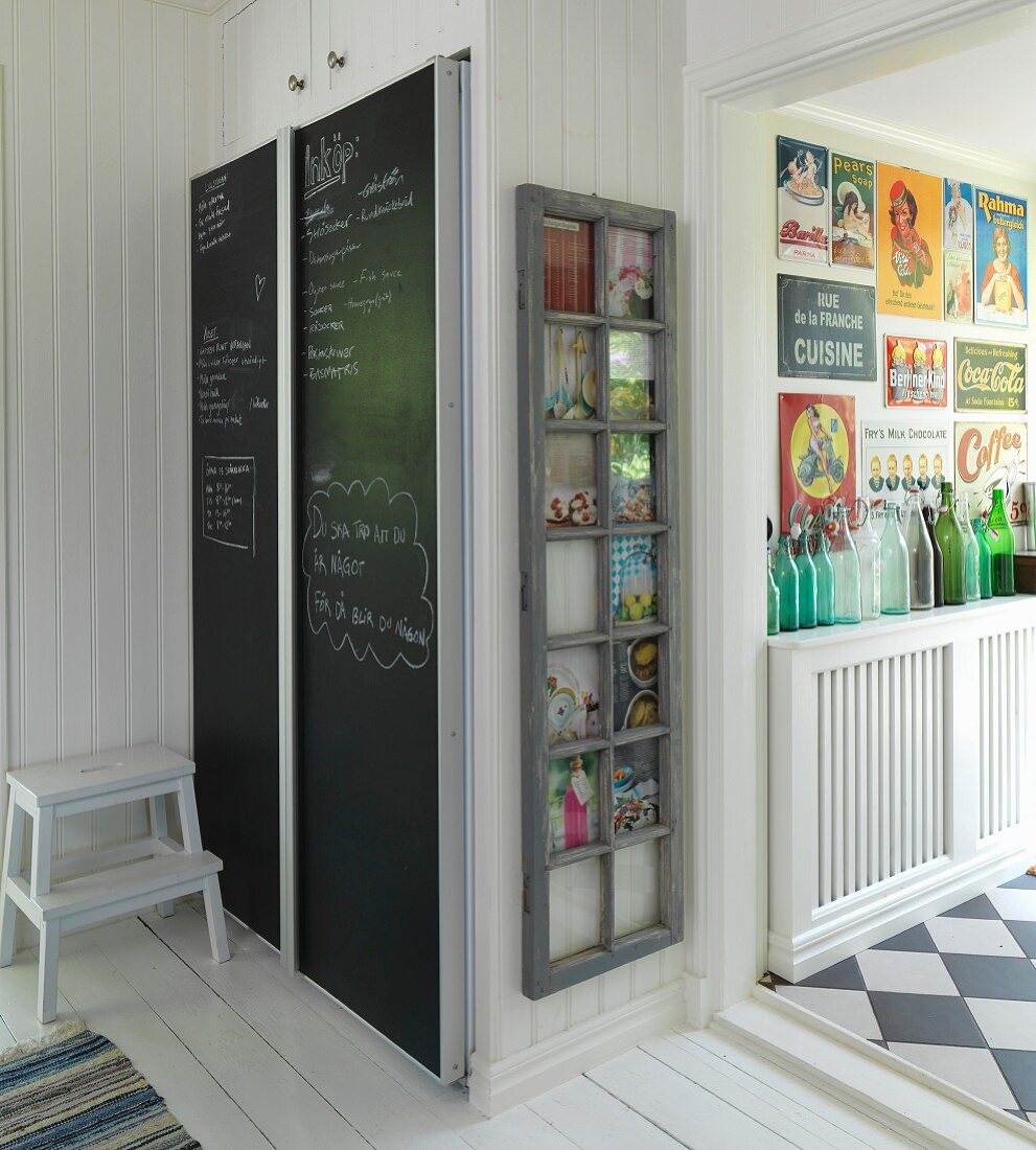 Eingebauter Kühlschrank mit Schiefertafel an der Tür und alter Fensterrahmen an der Wand
