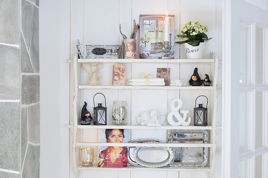 White shelves decorated with candles, trays and pictures in Scandinavian wooden house