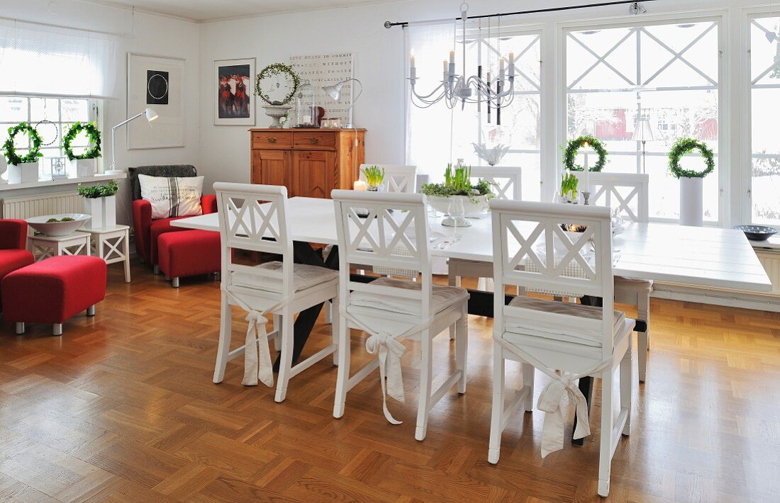 Scandinavian, country-house-style interior with white-painted dining set, red armchairs and Advent wreaths in windows