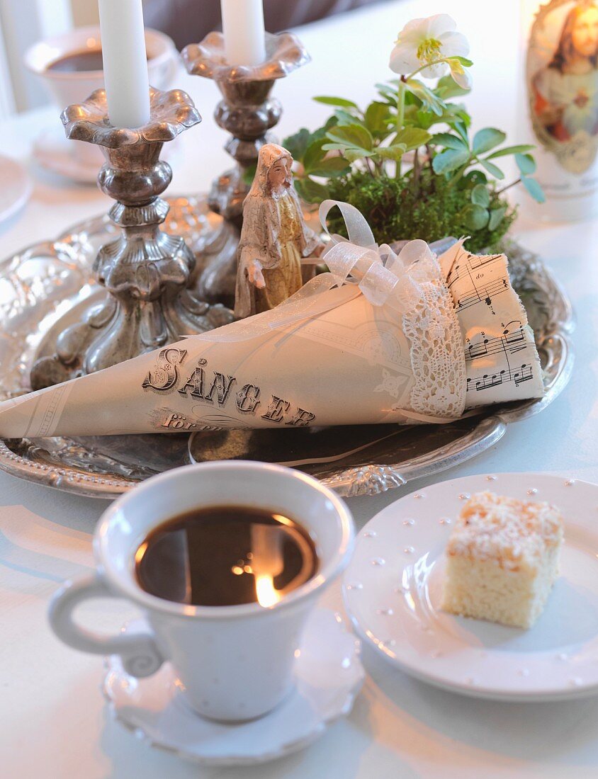 Coffee, slice of cake and silver tray holding lit candles in candlesticks
