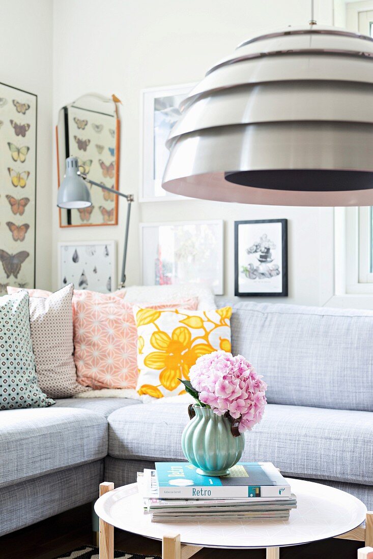 Pendant lamp with metal lampshade above side table and sofa with retro scatter cushions