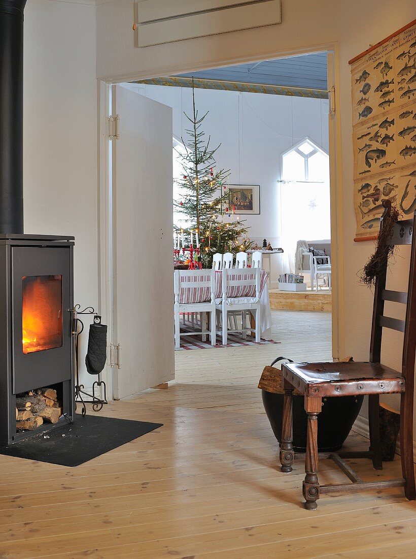 Antikstuhl vor Schwedenofen, Zimmerflucht auf Essplatz und Weihnachtsbaum in Wohnraum