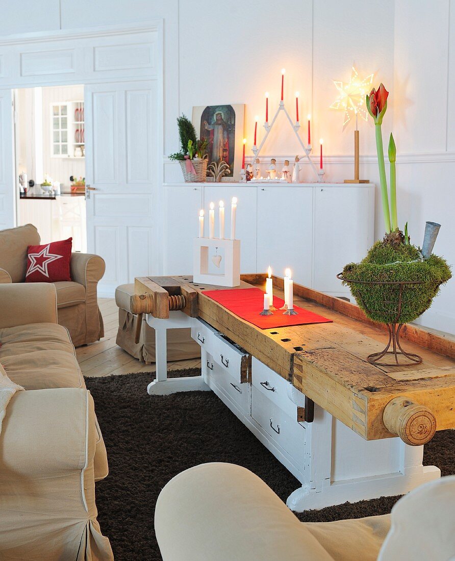 Sofa set and vintage table made from old workbench and chest of drawers; festive arrangements of candles and amaryllis