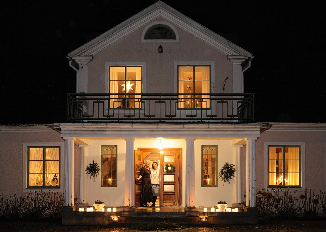 Illuminated villa at night with candlelit veranda