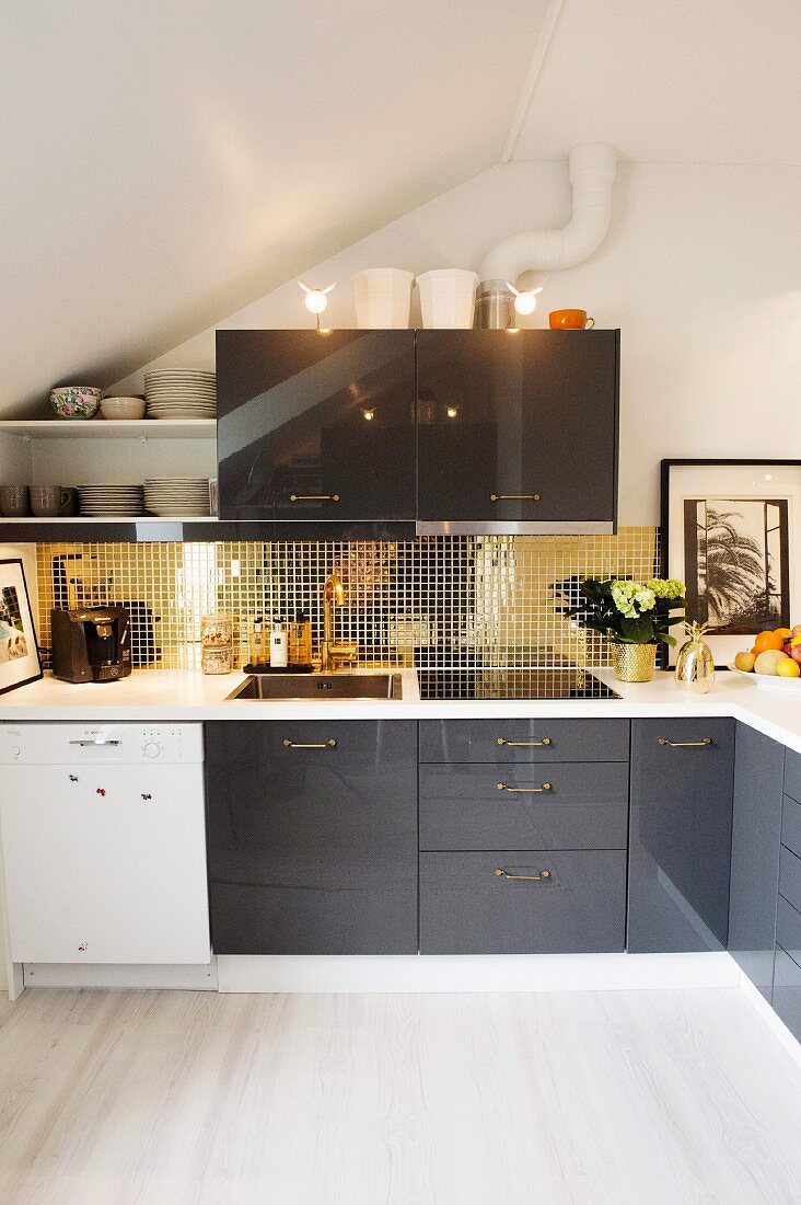 Moderne Küche unter dem Dach mit schwarzen und weissen Schrankfronten, Spritzschutz hinter Küchenzeile aus goldglänzenden Mosaikfliesen