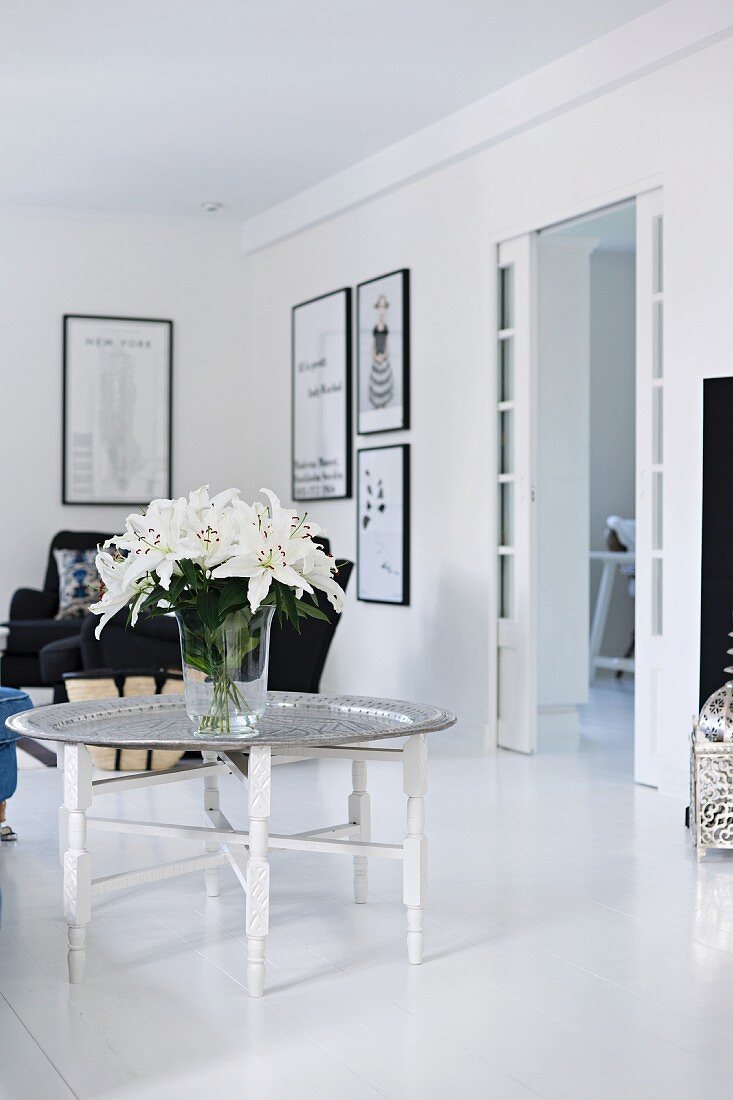 Weißer Lilienstrauß auf Tabletttisch in schwarz-weißem Wohnzimmer