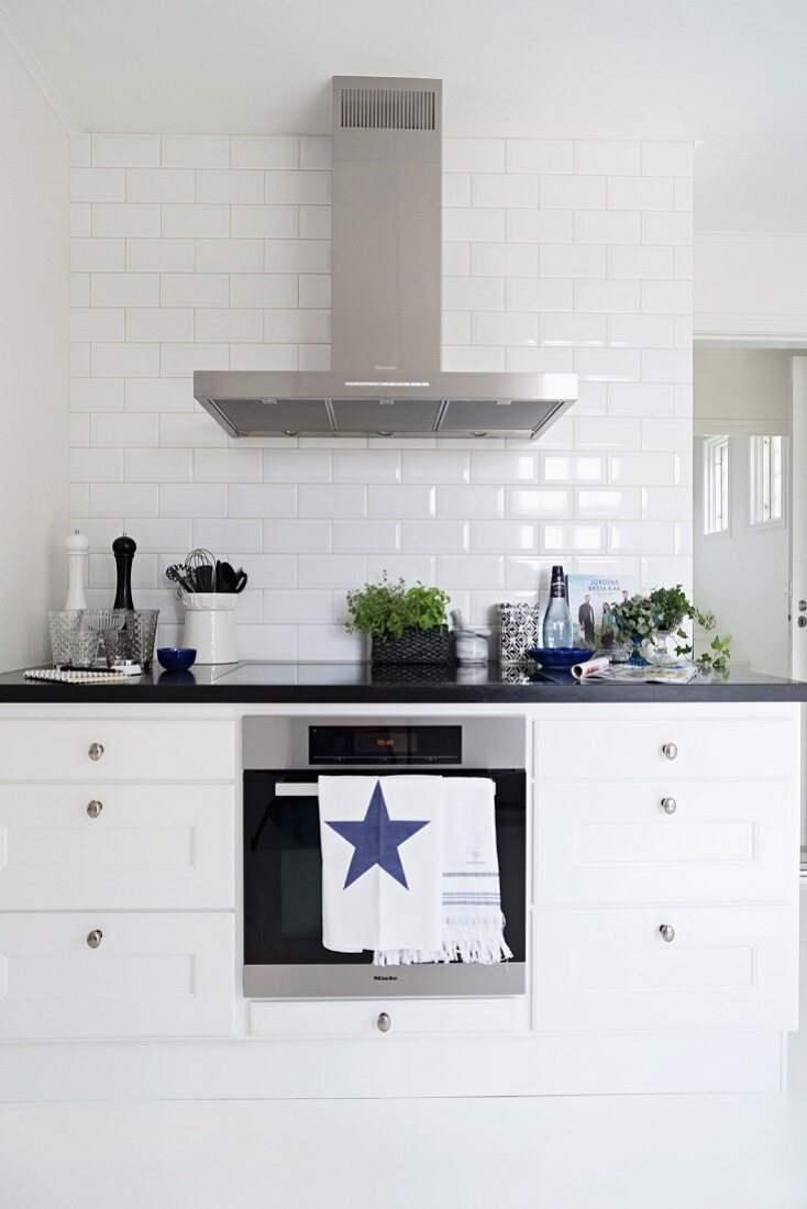 Black and white kitchen counter with stainless steel extractor hood and subway tiles on wall