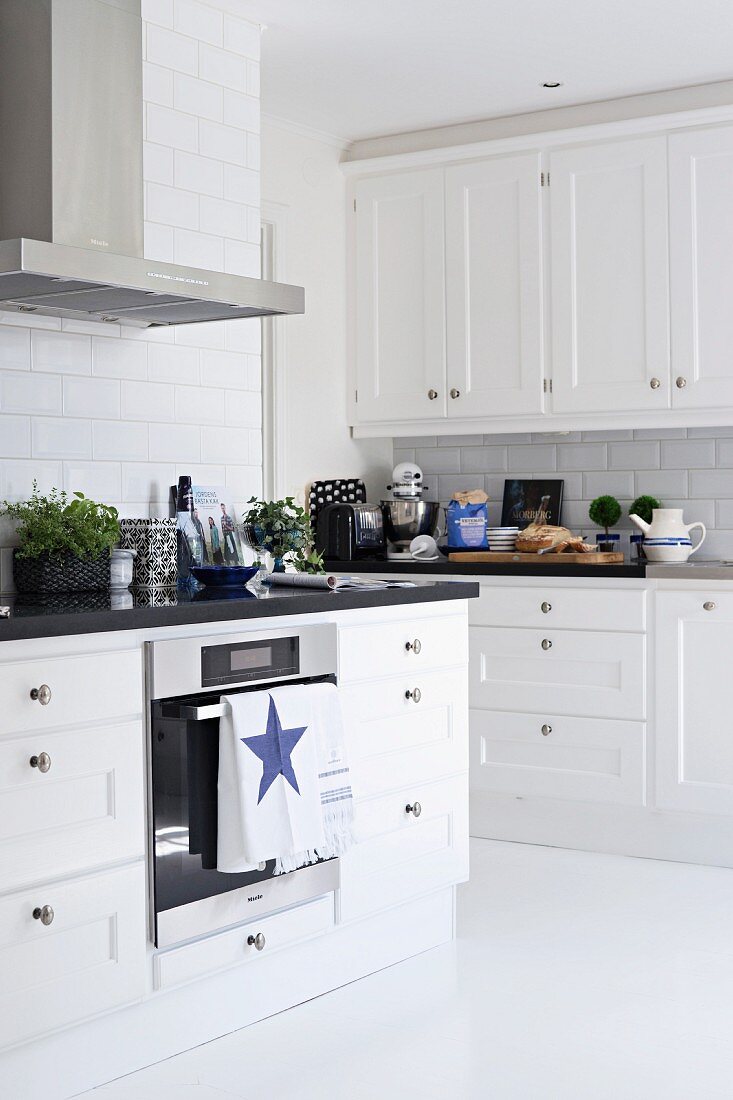 weiße Küche im skandinavischen Stil mit schwarzer Arbeitsplatte; Geschirrtuch mit Sternmotiv