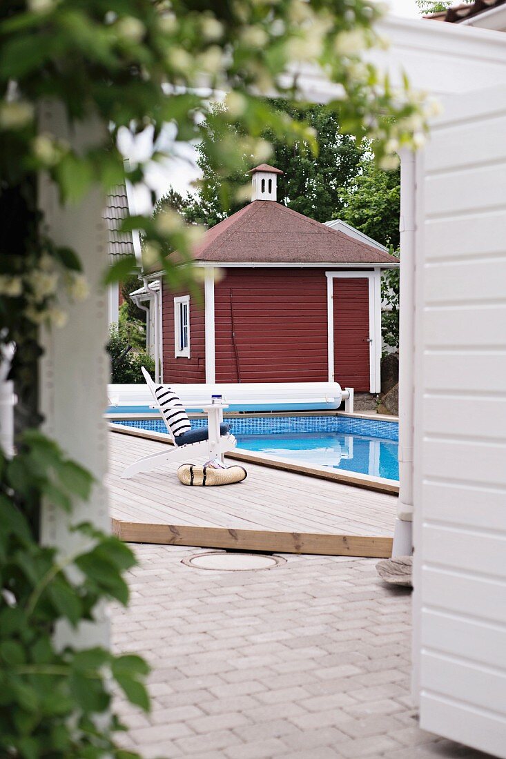 Swimming pool and Swedish, wooden summer house painted Falu red and white