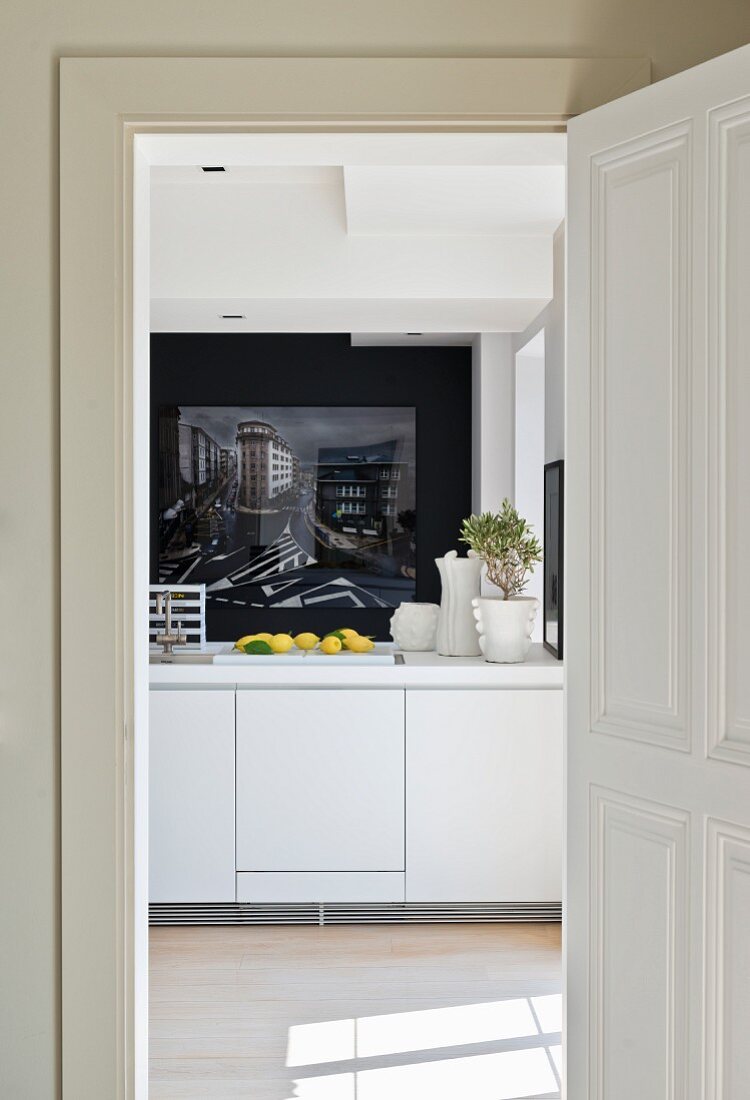 Blick durch offene Tür in moderne Küche mit weisser Küchenzeile und Fotokunst