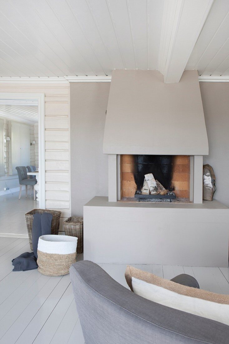Open fireplace with surround painted pale grey in wood-clad interior