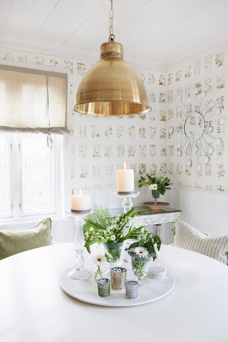 Drehbare Platte mit Blumensträussen und Windlichtern auf rundem, weißem Tisch im Esszimmer