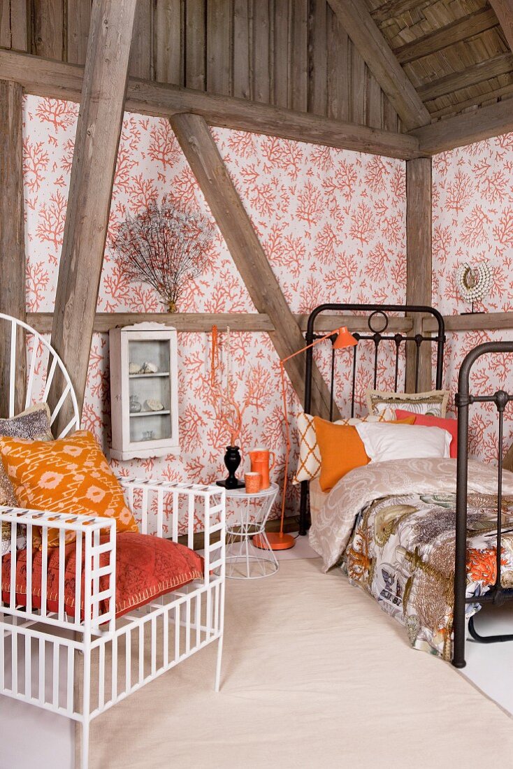 White, metal, throne-style chair with orange cushions, black metal bed and half-timbered walls with wallpaper panels